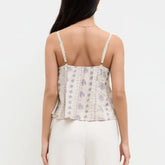 Woman wearing a floral strappy top with a plain background